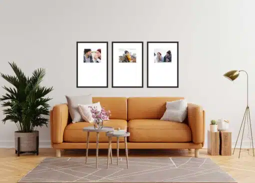 Modern living room with an orange sofa, three framed pictures on the wall, a floor lamp, and a potted plant.