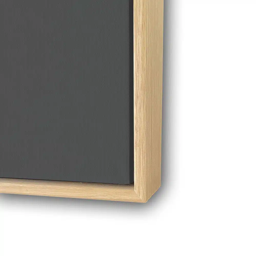 Close-up of a light wood frame with a deep recessed border holding a dark-colored artwork or panel.